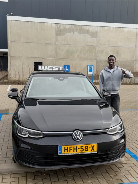 Geslaagde leerling geeft een duim omhoog naast de WEST-lesauto