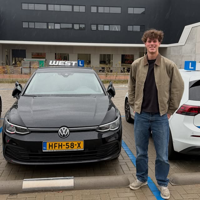Geslaagde leerling poseert trots bij de WEST-lesauto